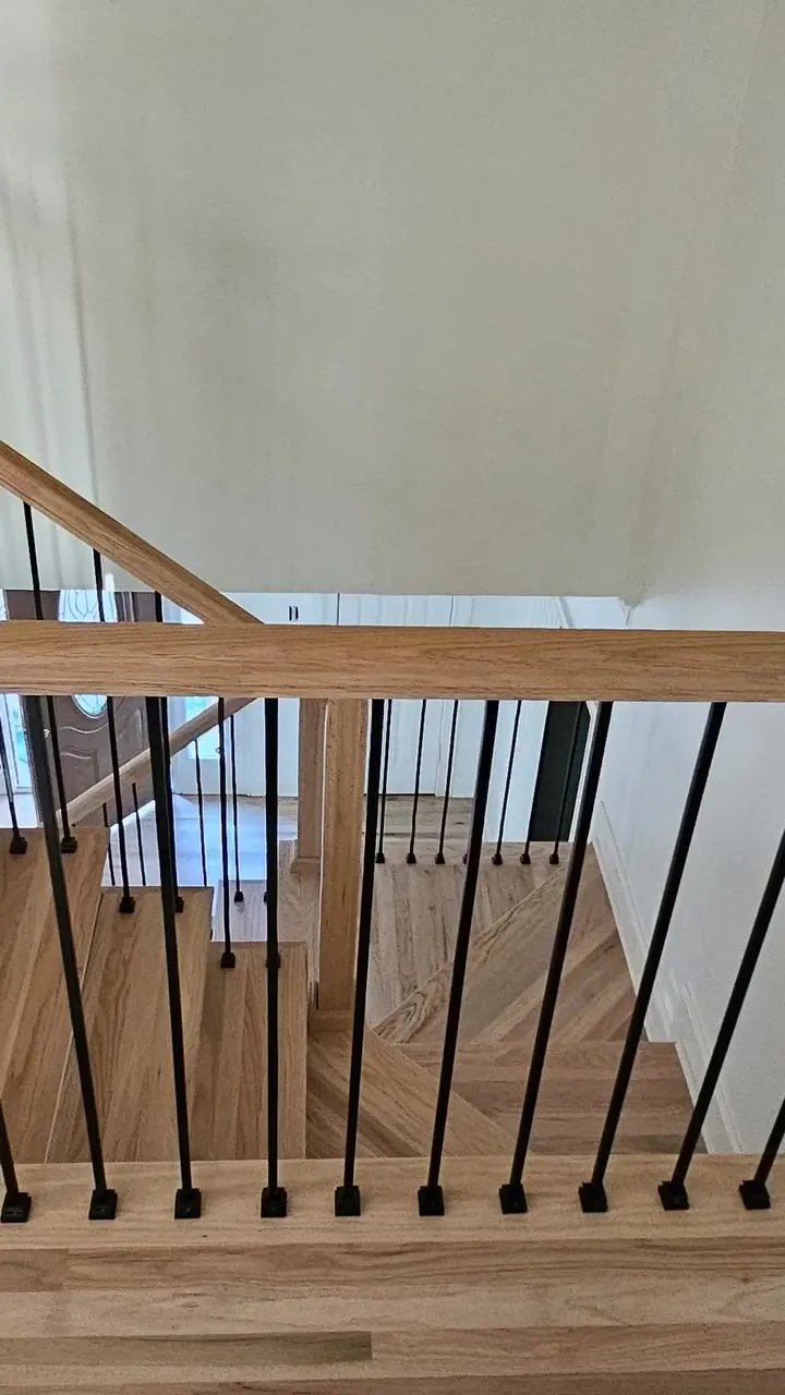 After: oak handrail and matte black balusters at the upper landing of a Huntsville hardwood stair makeover