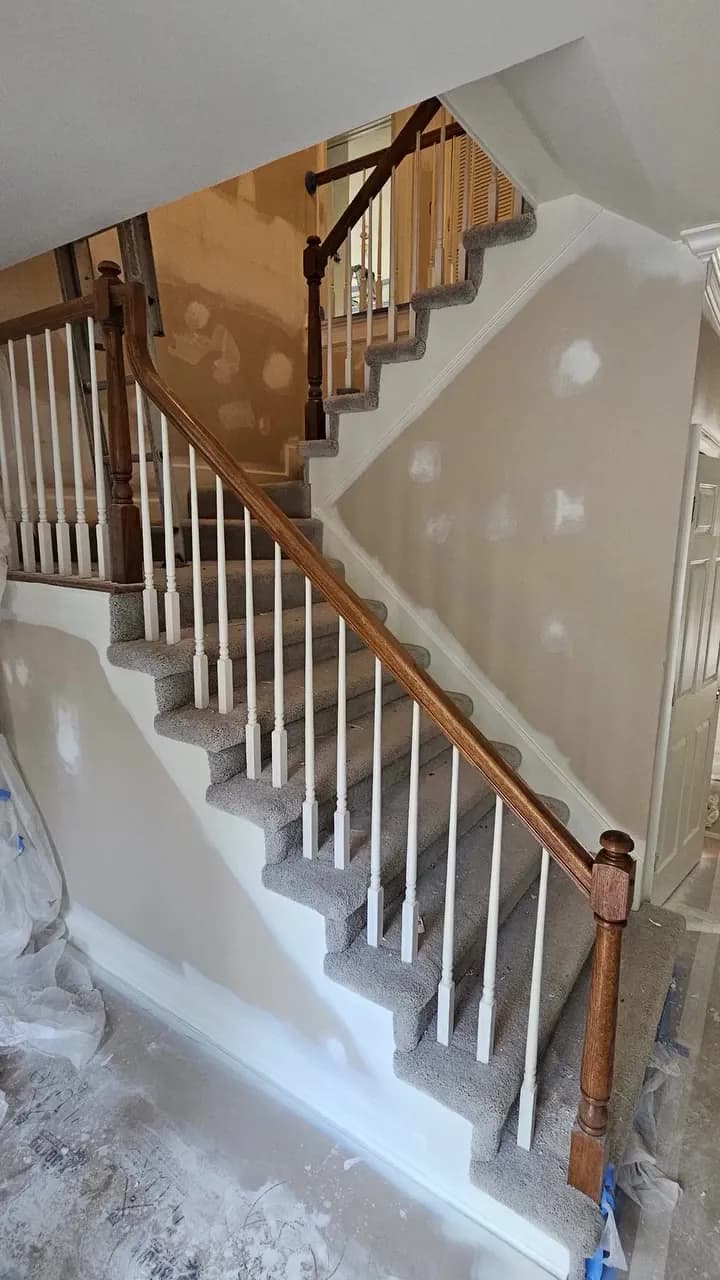 Before: carpeted Huntsville staircase with white turned spindles, a wood cap, and unfinished drywall