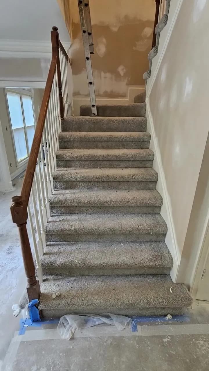 Before: looking up a carpeted Huntsville stair run with builder rails still in place