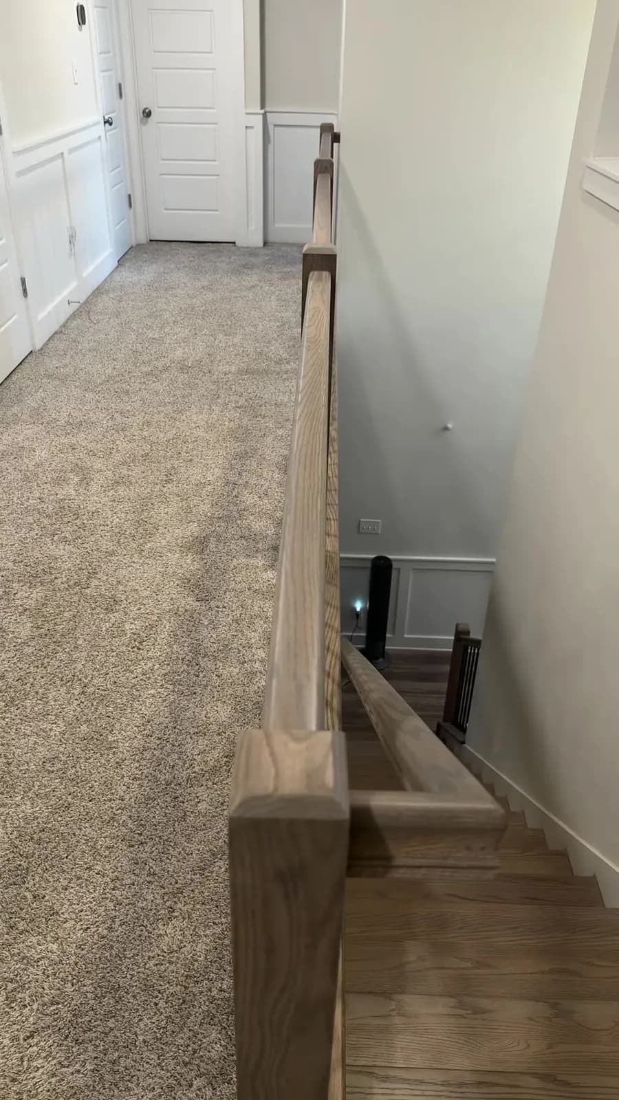 Close view of an oak handrail and newel on the upper landing after a Madison interior railing replacement