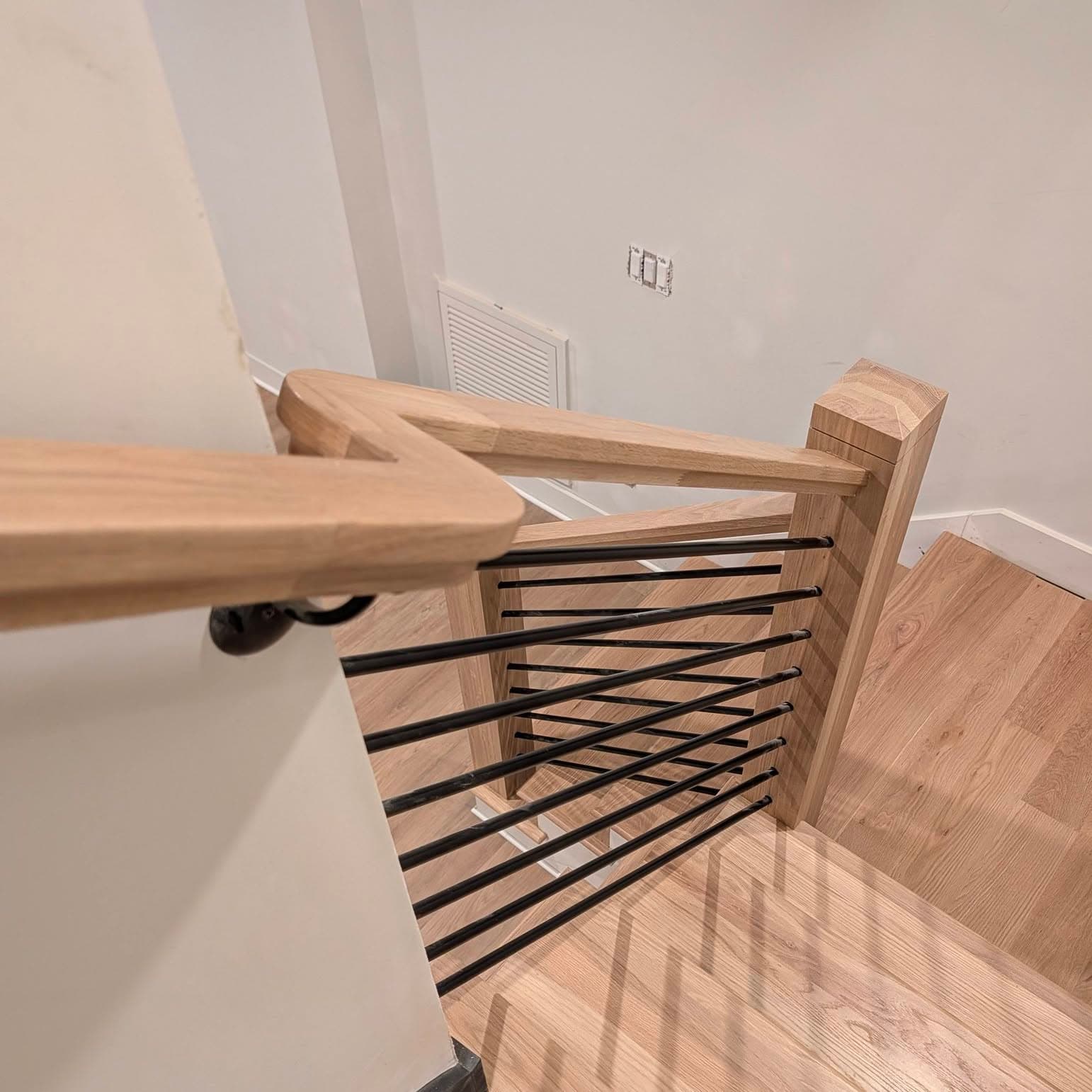 Upper stair landing with a light oak cap and horizontal matte black metal balusters, Rocket City Stairs