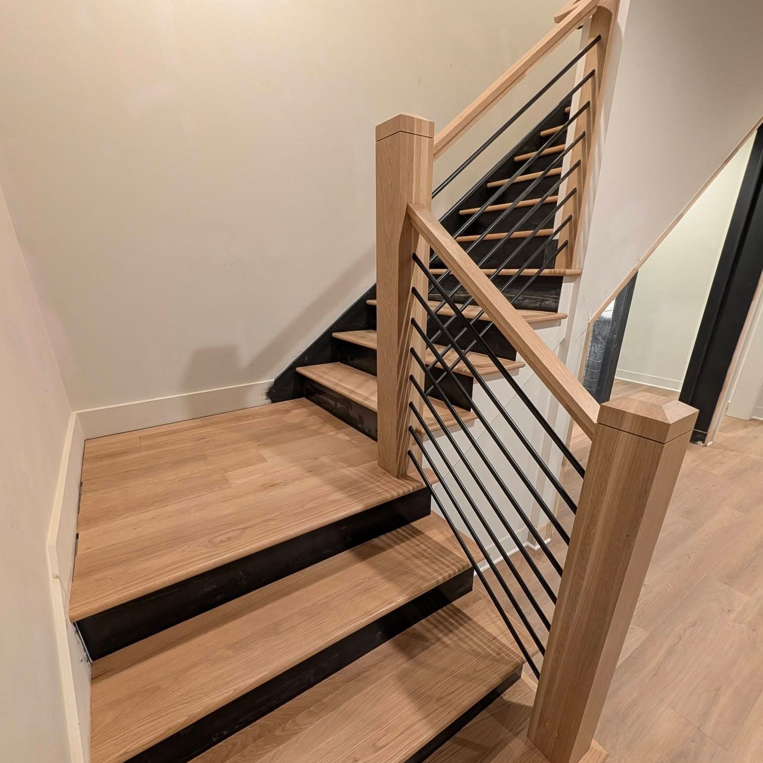 Stair run with light oak treads, dark risers, and black metal balusters, Rocket City Stairs