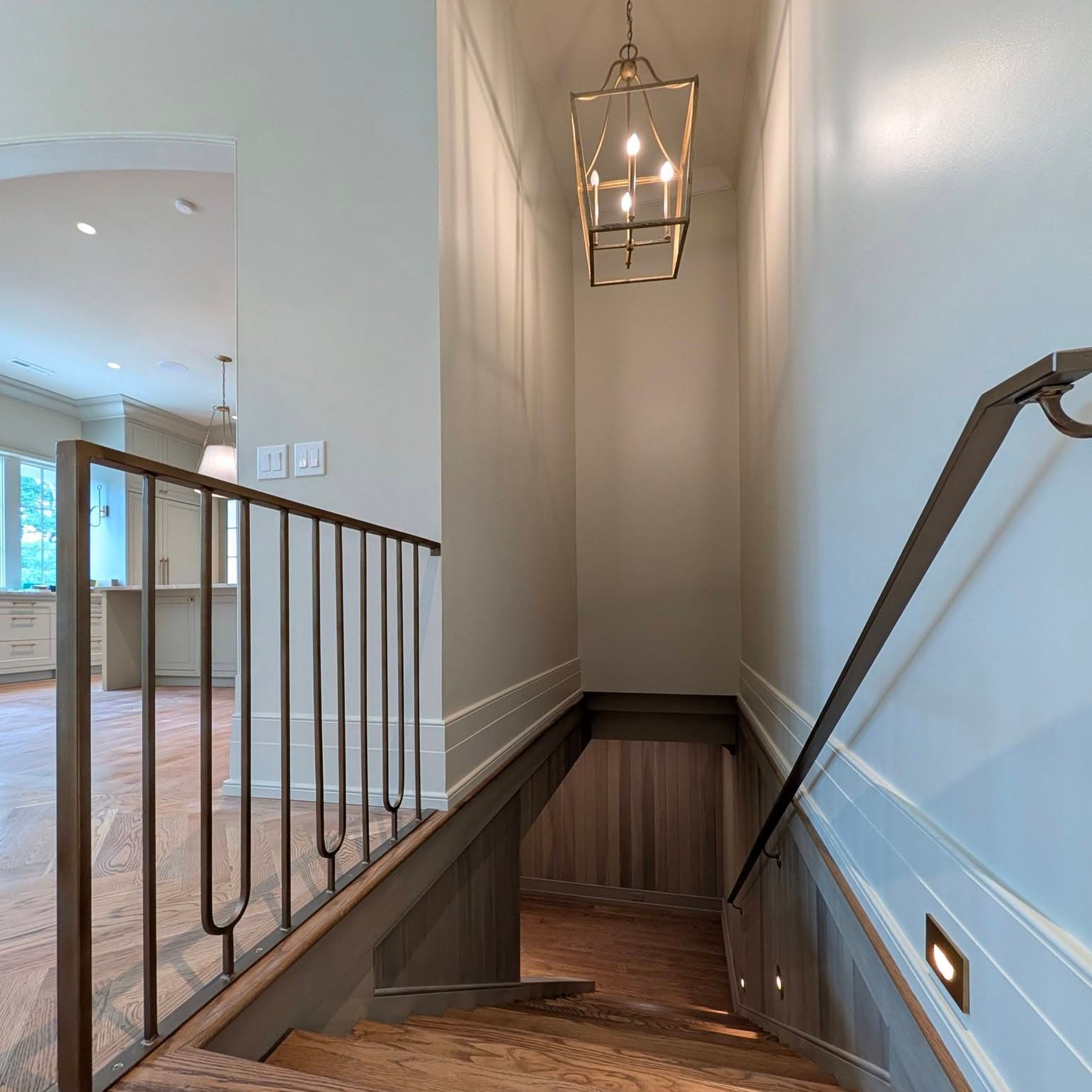 Interior stair railing with black metal balusters and a wood cap over hardwood, Rocket City Stairs